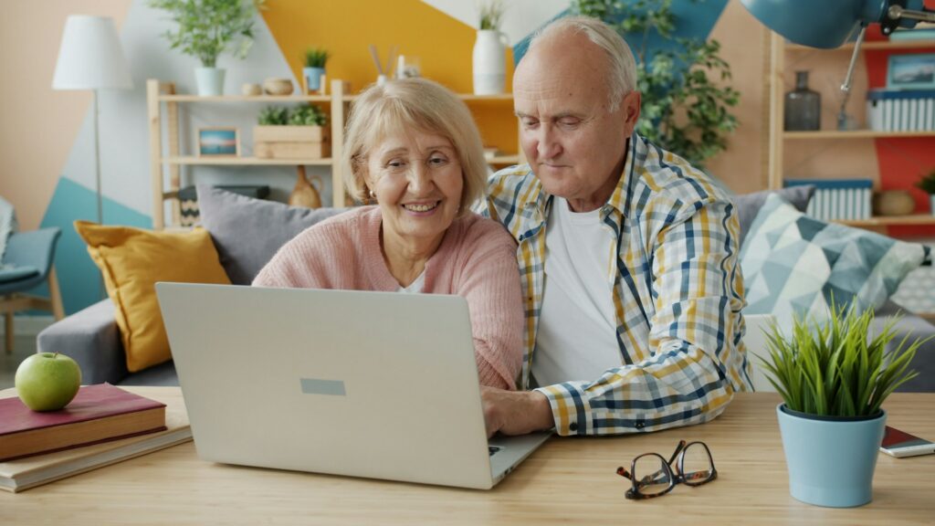 Couple de seniors souriant devant un ordinateur portable, à la maison