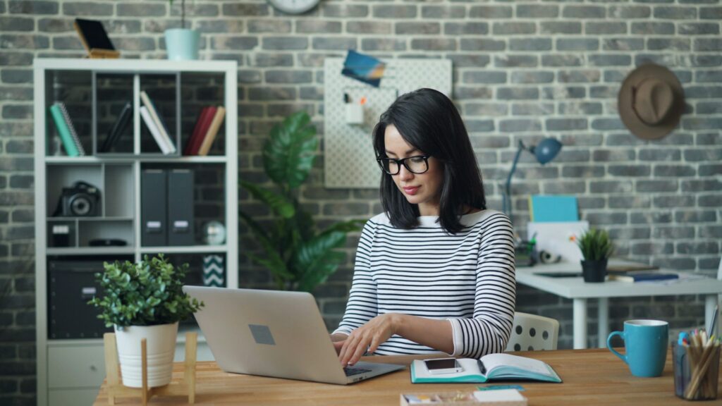 Indépendante à lunettes assise à son bureau, devant son ordinateur
